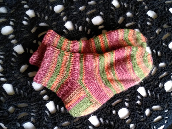 About me: colourful knitted socks on a black crochet scarf with a skull pattern