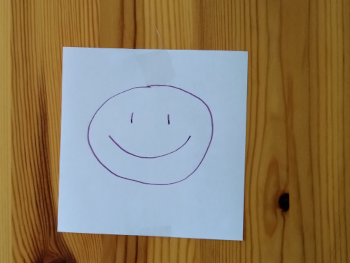 About me: smiley drewn in purple ink on a white square piece of paper
