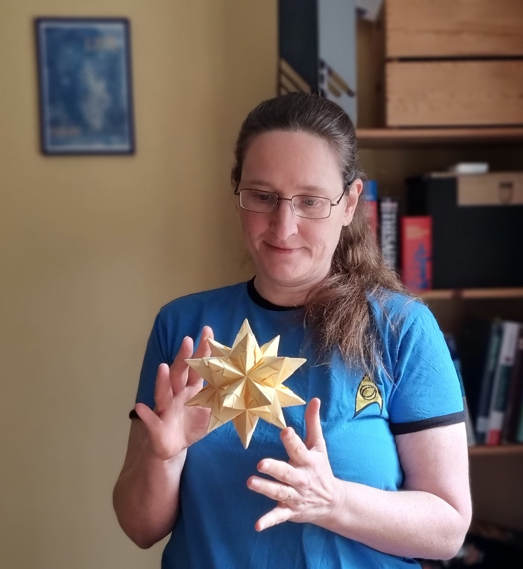 tutoring for school or university: a woman in a star trek fan shirt marvels at a three dimensional star made from yellow paper